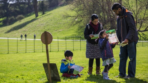 Parents with two children looking at trail sheets in parkland